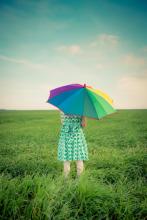 petite fille au parapluie arc en ciel sur une colline